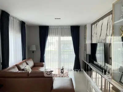 Modern living room with leather sofa and large TV, featuring elegant curtains and marble accent wall.