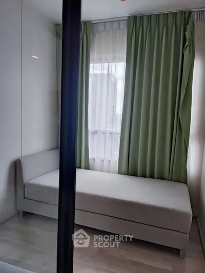 Cozy bedroom with modern decor and large window with green curtains.