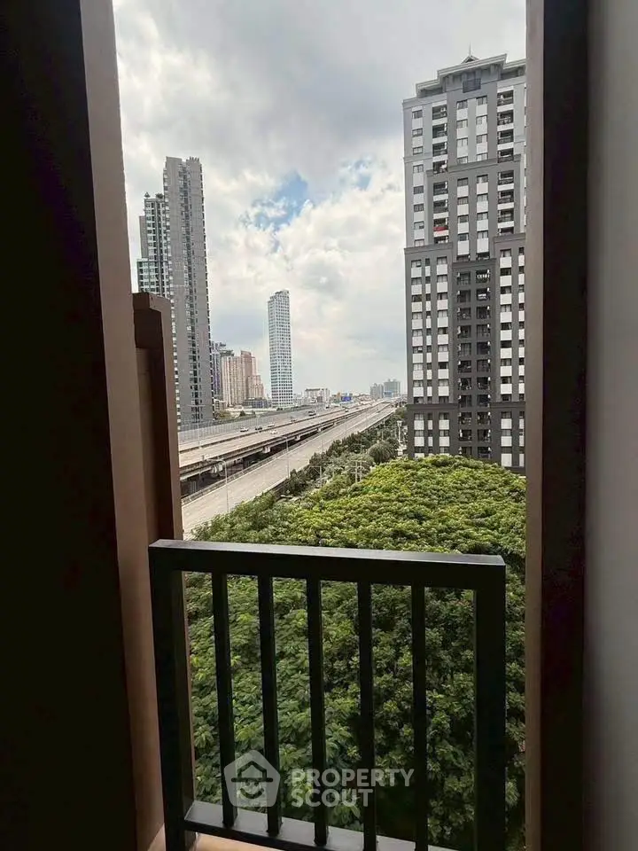 Stunning urban view from a high-rise balcony overlooking city skyline and lush greenery.