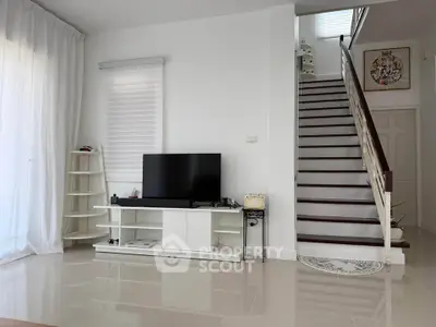 Modern living room with sleek TV stand and elegant staircase in bright, airy space.