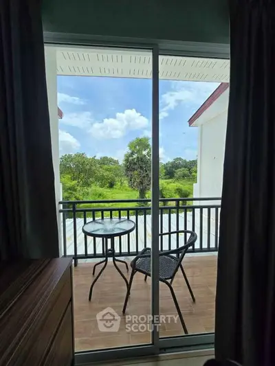 Charming balcony view with outdoor seating overlooking lush greenery and blue skies.