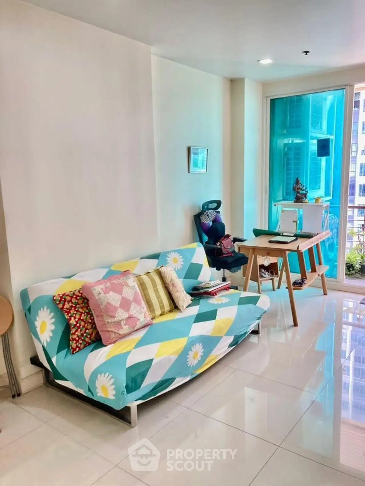 Bright living room with colorful sofa and modern decor in high-rise apartment.