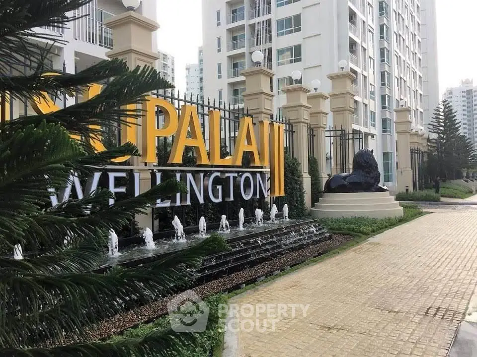 Elegant entrance of luxury apartment complex with modern architecture and water feature.