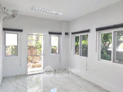 Bright and airy room with large windows and garden view, perfect for a serene living space.