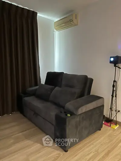 Cozy living room with plush dark sofa and modern projector setup.