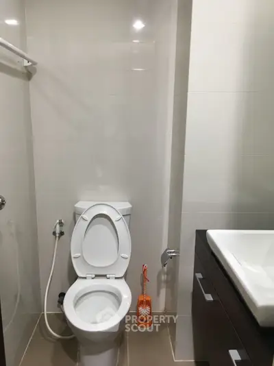 Modern bathroom with sleek fixtures and a clean design, featuring a toilet and sink.