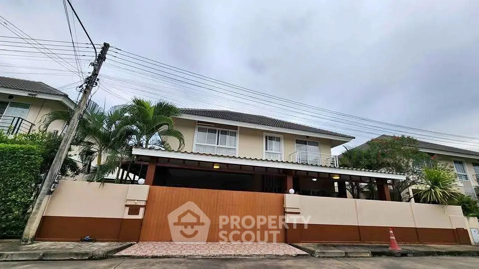 Charming two-story house with lush greenery and secure gated entrance in a serene neighborhood.