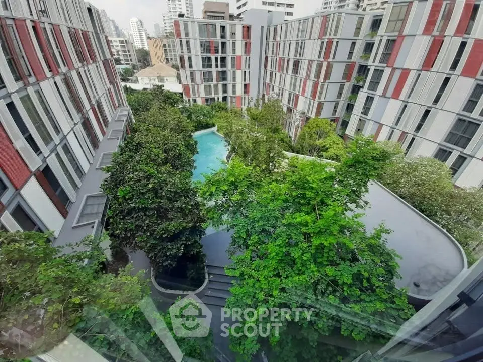 Modern urban apartment complex with lush greenery and central pool view.