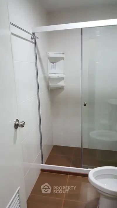 Modern bathroom with glass shower enclosure and sleek white fixtures.
