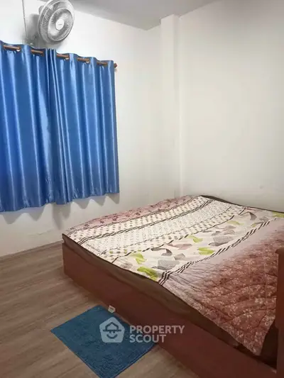 Cozy bedroom with wooden flooring and blue curtains, perfect for a restful retreat.