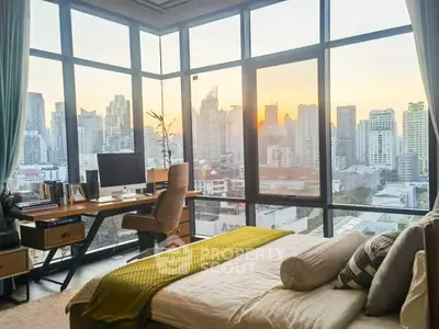 Luxurious bedroom with stunning city skyline view and modern workspace.