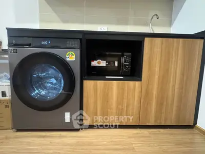Modern laundry area with washing machine and microwave in sleek cabinetry