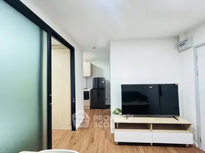 Modern living room with sleek TV setup and open kitchen view, perfect for urban living.