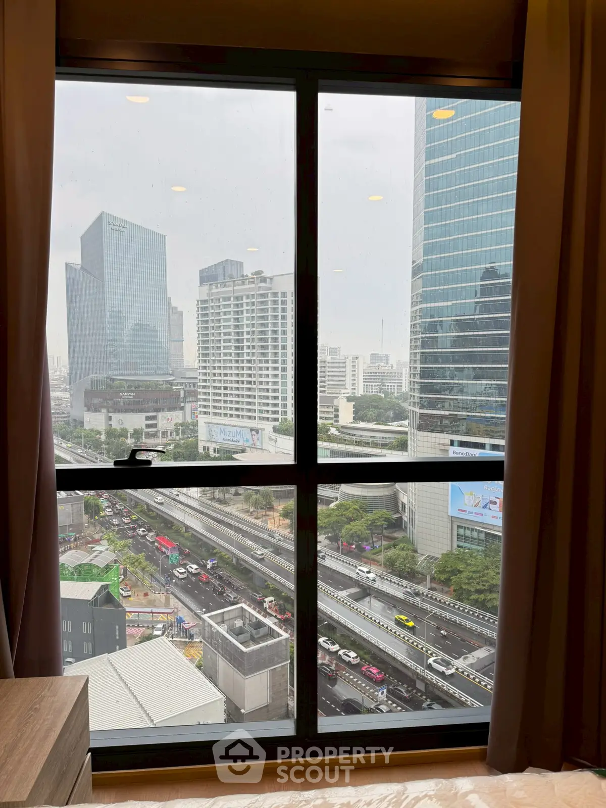 Stunning cityscape view from a high-rise apartment window, showcasing urban skyline and bustling streets.
