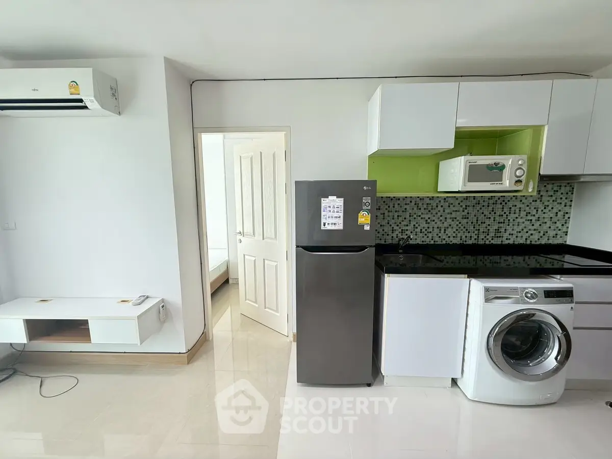 Modern apartment kitchen with washing machine and fridge, open layout design.