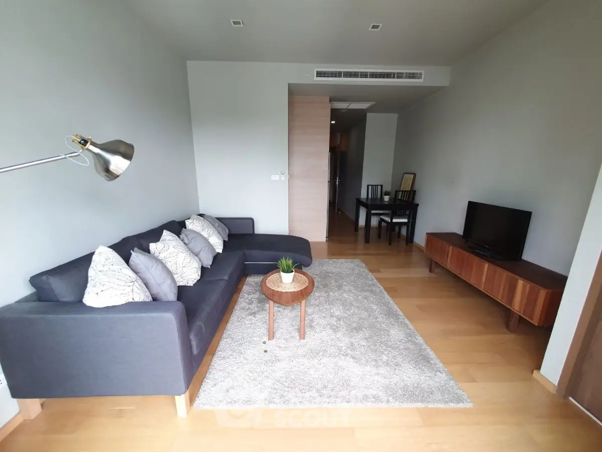 Modern living room with stylish sofa, TV, and dining area in open layout