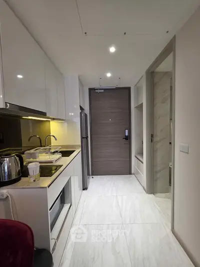 Modern kitchen with sleek white cabinets and built-in appliances in a compact layout.