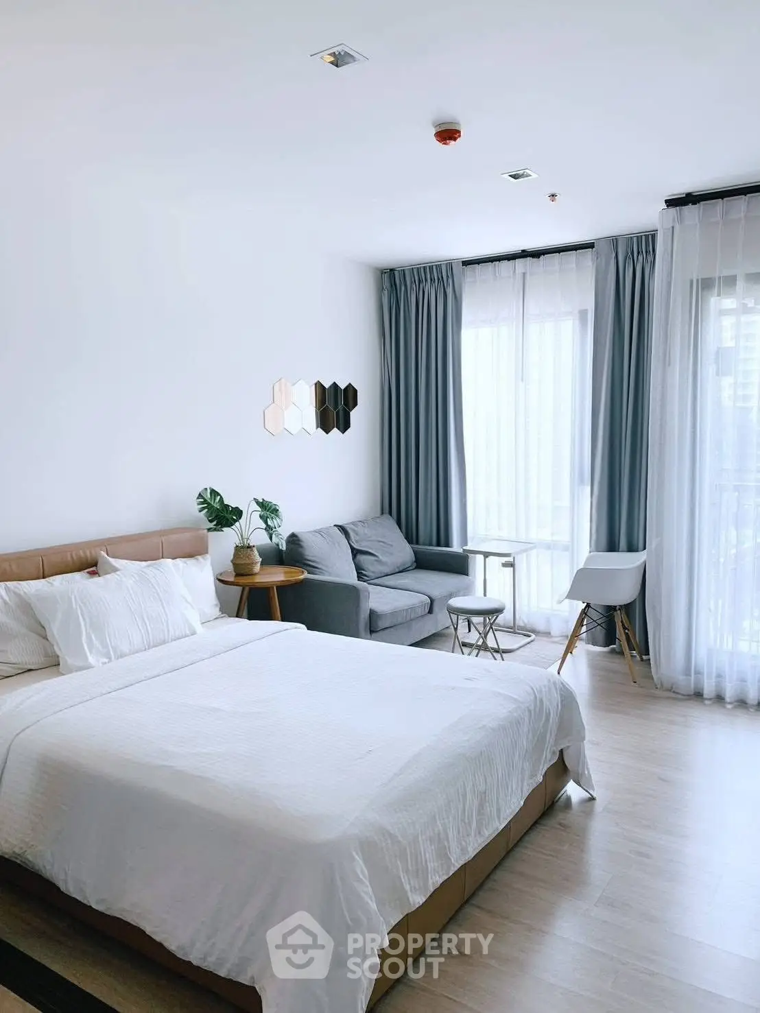 Modern bedroom with elegant decor and natural light, featuring a cozy seating area.