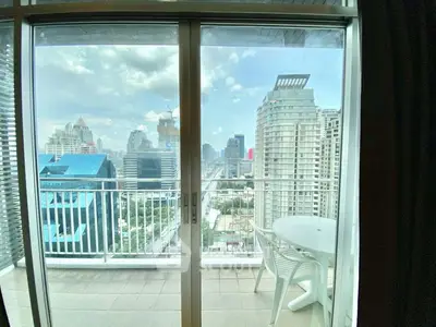 Stunning city view from modern balcony with glass doors and outdoor seating.