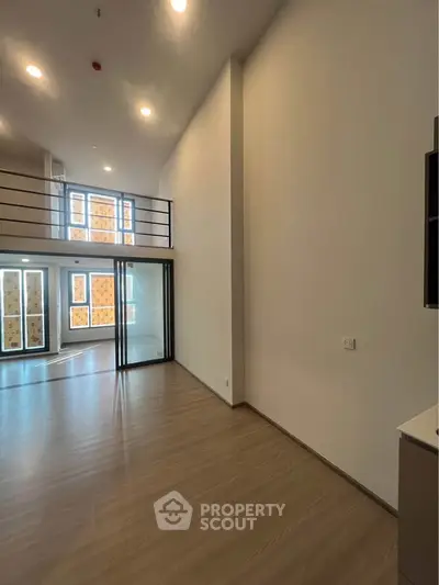 Spacious modern living room with high ceilings and large windows in a contemporary apartment.