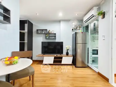 Modern living room with sleek TV unit and adjacent kitchen featuring stainless steel appliances.