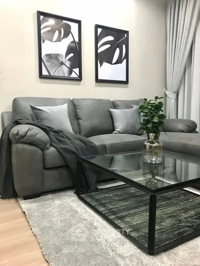Stylish living room with modern gray sofa and glass coffee table, perfect for cozy relaxation.