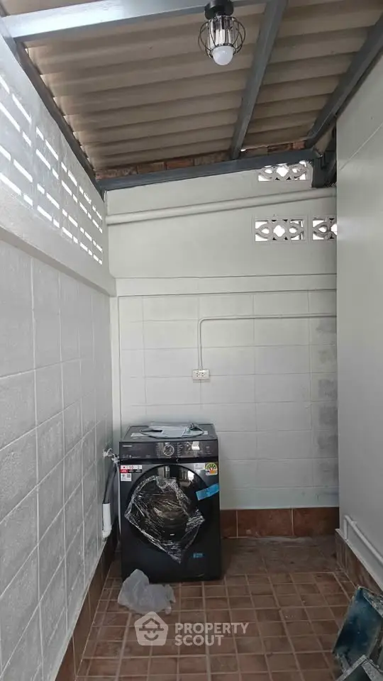 Covered outdoor laundry area with washing machine and tiled flooring.
