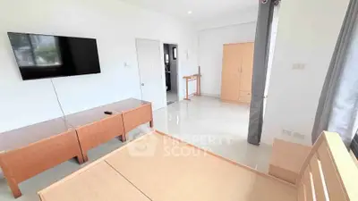 Spacious bedroom with modern furniture and wall-mounted TV in bright apartment.
