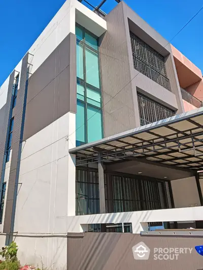 Modern multi-story building with sleek design and large windows under clear blue sky.