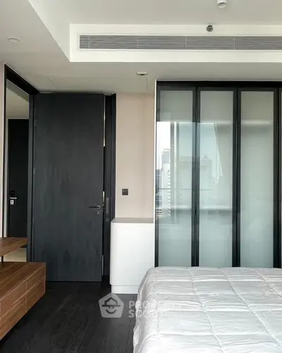 Modern bedroom with sleek design and city view through large windows.