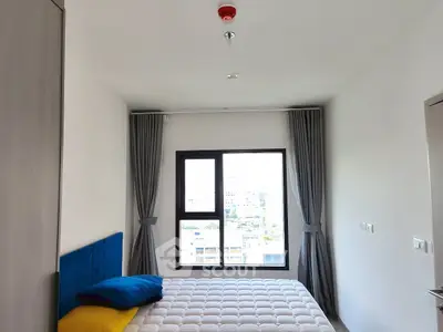 Modern bedroom with large window and stylish curtains, offering a bright and airy ambiance.