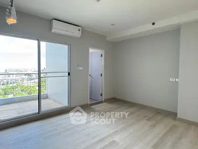 Spacious modern living room with balcony and city view, featuring sleek flooring and air conditioning.