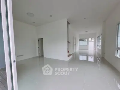 Spacious modern living room with glossy tiled floors and large windows for natural light.