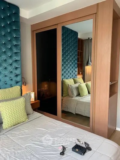 Luxurious bedroom with plush teal headboard and mirrored wardrobe, perfect for modern living.