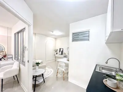 Modern open-plan living room and kitchen with sleek white decor and cozy seating area.