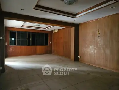 Spacious empty room with wooden paneling and tiled floor, ideal for customization.