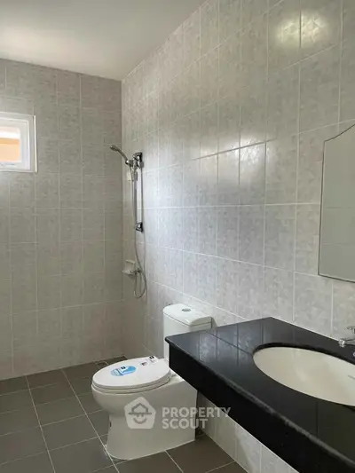 Modern bathroom with sleek black countertop and tiled walls