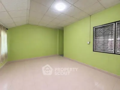 Spacious empty room with green walls and tiled floor, perfect for customization.