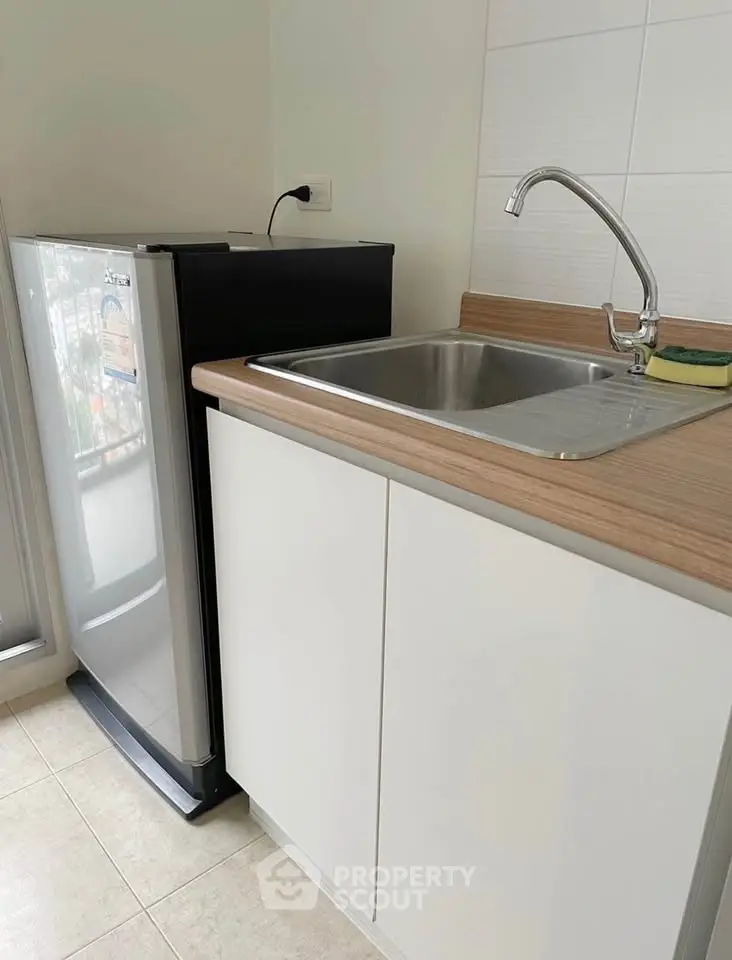 Modern kitchen with sleek fridge and stainless steel sink, perfect for compact spaces.