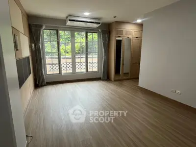 Spacious empty room with large windows and wooden flooring, ideal for customization.