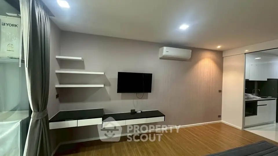 Modern living room with sleek TV setup and open kitchen layout