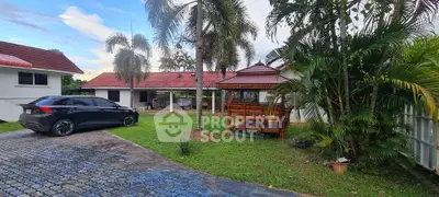 Charming tropical garden with gazebo and parked car in serene residential area.