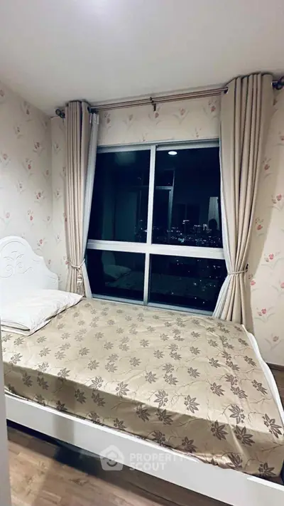 Cozy bedroom with large window offering stunning city view, elegant floral wallpaper, and stylish curtains.