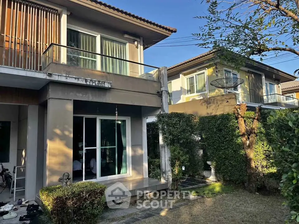 Charming two-story house with lush garden and modern balcony in serene neighborhood.