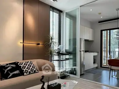Modern living room with open kitchen, stylish decor, and natural light.