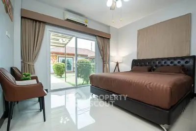 Spacious bedroom with modern decor and garden view, featuring a large bed and sliding glass doors.