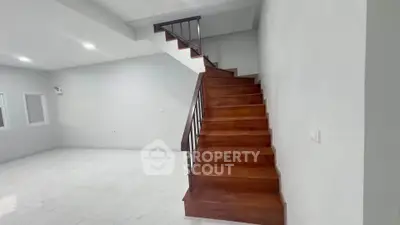 Spacious modern living room with elegant wooden staircase and bright lighting.