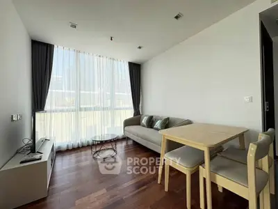 Modern living room with large window, wooden flooring, and minimalist furniture in a bright apartment.