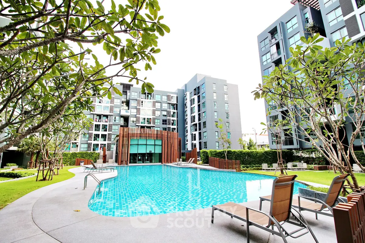Luxurious modern apartment complex with a stunning outdoor pool and lush greenery.