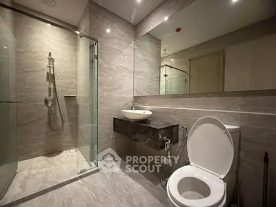 Luxurious modern bathroom with elegant marble tiles and sleek glass shower enclosure.